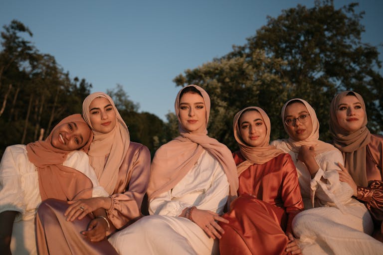 A group of women wearing traditional hijabs enjoying the outdoors at sunset.
